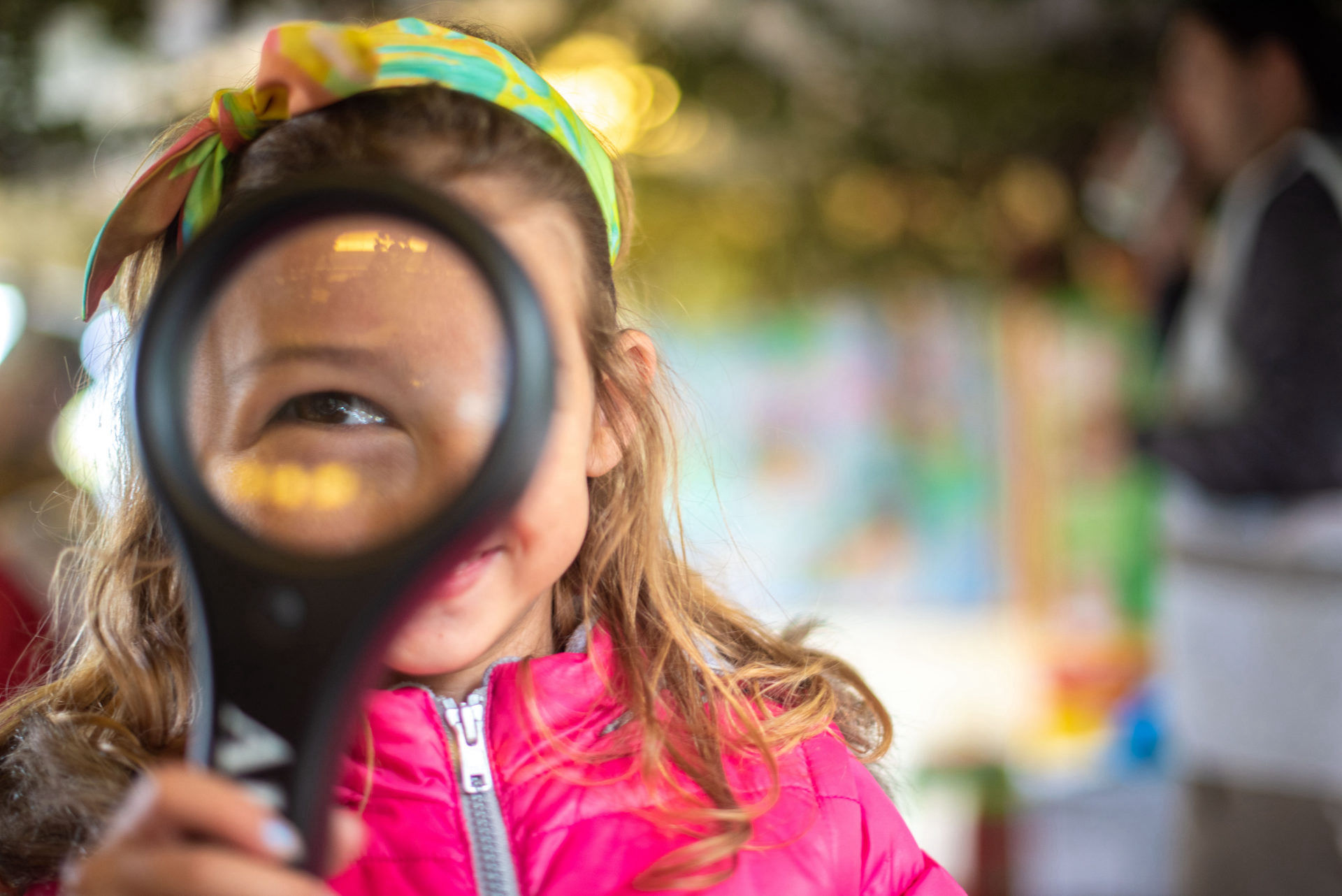 A girl with a magnifying glass over her eye at a Manx Wildlife Trust invertebrate class